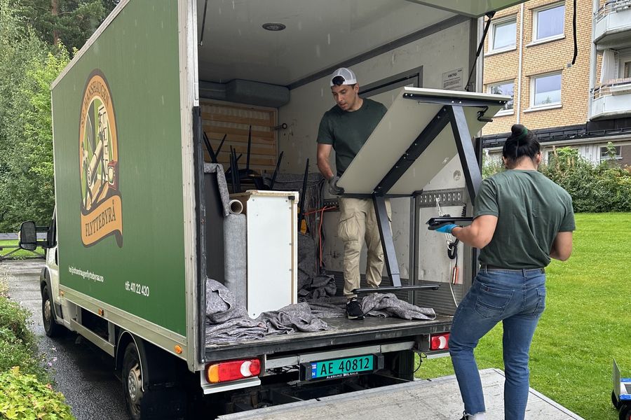Mannskapet laster et skrivebord inn i flyttebilen utenfor en bygård i Oslo